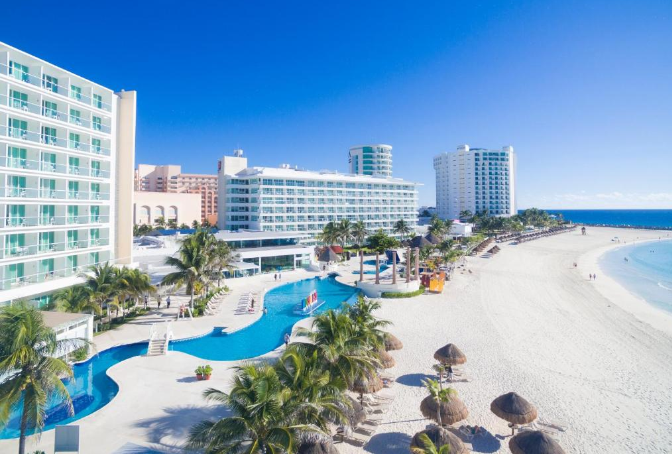 Fachada elegante del Hotel Krystal Cancun, ubicado en la hermosa zona hotelera de Cancún. Descubre la sofisticación y la comodidad en este hotel frente al mar, con habitaciones modernas, piscinas impresionantes y acceso directo a las playas de arena blanca. Experimenta la hospitalidad excepcional y disfruta de una estancia inolvidable en el Krystal Cancun.